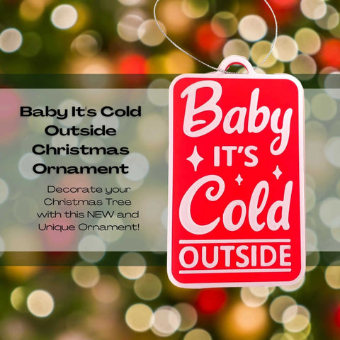 The Chatelet Manufacturing “Baby Its Cold Outside Christmas Ornament” hangs on a tree amid festive lights. Made in the USA, this decorative holiday ornament adds cheerful charm to your seasonal décor.