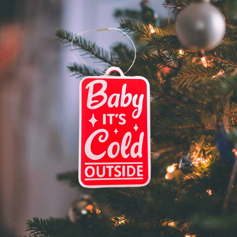 The Baby Its Cold Outside Christmas Ornament by Chatelet Manufacturing glows on the tree under warm lights, adding festive charm. This decorative holiday ornament is proudly made in the USA.