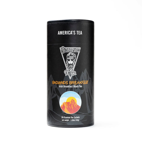 A black cylindrical container from Sasquatch Tea Co holds Badlands Breakfast (Irish Breakfast Tea) with a mountain illustration and label noting 20 premium caffeinated tea sachets inside.