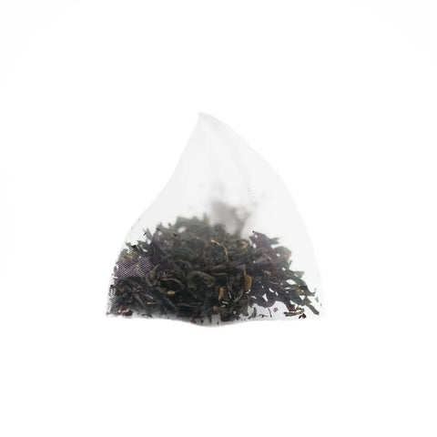 A triangular, transparent tea bag of Sasquatch Tea Co’s Badlands Breakfast (Irish Breakfast Tea) rests on a plain white background, offering a bold and caffeinated loose leaf experience.