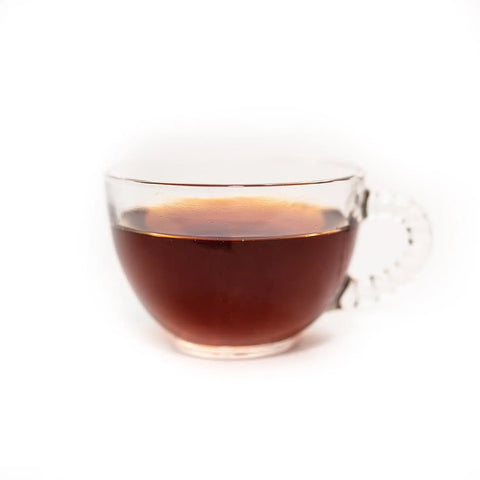 A clear glass cup of Sasquatch Tea Co Badlands Breakfast (Irish Breakfast Tea) sits against a white background, highlighting the rich color and classic caffeinated appeal of this blend.