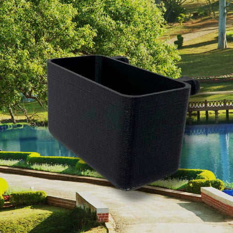 A BOGLETS Organizer Charm Accessory by Chatelet Manufacturing, compatible with Bogg Bags and perfect for keeping keys or personal items handy, floats above a landscaped park with green lawns, trees, bushes, and a blue pond.