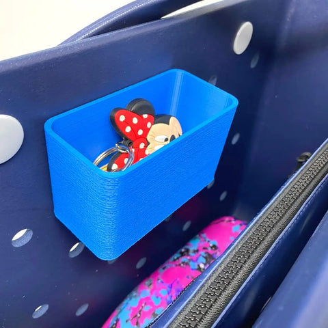 A BOGLETS Organizer Charm Accessory by Chatelet Manufacturing is attached inside a navy blue bag, along with a colorful pink and purple zippered pouch for organizing keys or personal items.