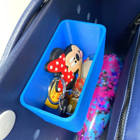 The BOGLETS Organizer Charm Accessory by Chatelet Manufacturing keeps keys with a Minnie Mouse keychain, a yellow measuring tape, and small items organized in your navy tote bag. A colorful water bottle sits beside this handy accessory.