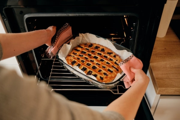 Person taking a tray of baked dish out of an oven