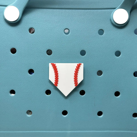 The BOGLETS Sport Charm by Chatelet Manufacturing, a white home plate with red stitching, attaches to rubber beach bags or similar totes, perfect for sports fans.