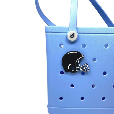 The Chatelet Manufacturing BOGLETS sport charm is a black football helmet designed for rubber beach bags and similar totes. It attaches easily to your light blue perforated bag with a round white button on the strap—perfect for customizing your style.