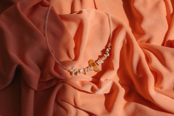 Necklace with amber beads on a draped orange fabric background