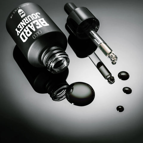 A black bottle of Cheryl Kelly & Co. Beard Journey Beard & Face Oil with a dropper rests on a sleek, reflective surface beside several drops of oil.
