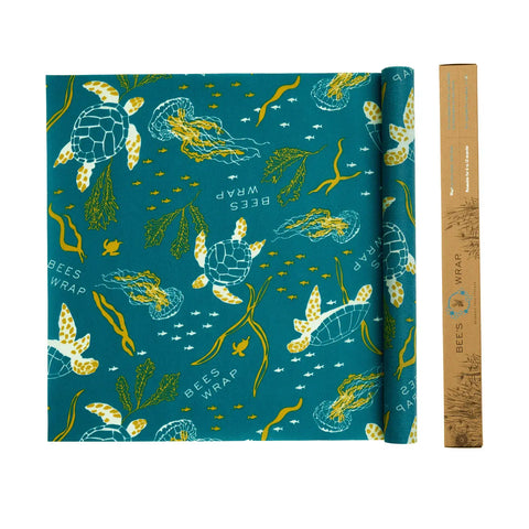 Bees Wrap Roll in teal, adorned with sea turtles, jellyfish, seaweed, and bubbles, sits beside its brown cardboard box—a customizable beeswax food wrap that’s a perfect plastic wrap alternative for home bakers.