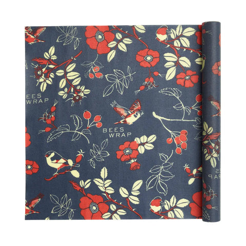 Bees Wrap Roll: A rolled beeswax wrap with a dark blue background, featuring red flowers, green leaves, berries, and cream birds. An eco-friendly plastic wrap alternative for home bakers.