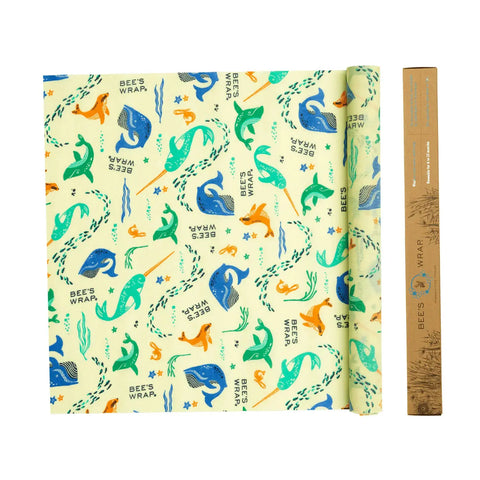 Bees Wrap Roll is a reusable food wrap featuring whales, seals, fish, and seaweed. This eco-friendly alternative to plastic wrap has a colorful design and comes in brown cardboard packaging shown on the right.