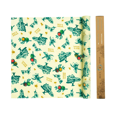 A rolled-out sheet of Bees Wrap Roll, a plastic wrap alternative with green illustrations on yellow, sits next to its rectangular brown Bees Wrap packaging.