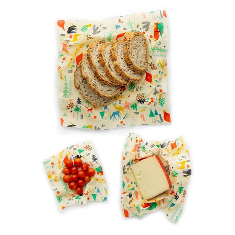 Multigrain bread, cherry tomatoes, and cheese stay fresh in Bees Wrap Assorted 3 Pack—colorful, plastic-free wraps with vibrant animal and nature prints on white.