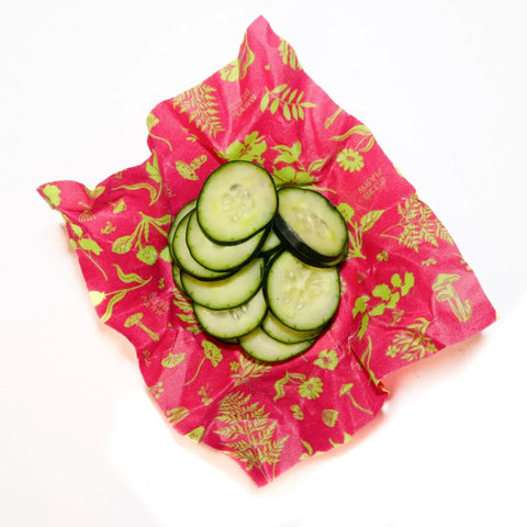 Sliced cucumber on a bright pink, botanical-patterned Bees Wrap—plastic-free and perfect for keeping food fresh. Featured here as part of the Bees Wrap Assorted 3 Pack.