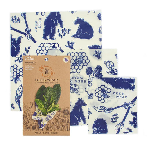 Bee’s Wrap Assorted 3 Pack includes three reusable food wraps in blue bear and nature patterns. Available in three sizes, these plastic-free wraps keep food fresh, shown with leafy greens wrapped for eco-friendly storage.