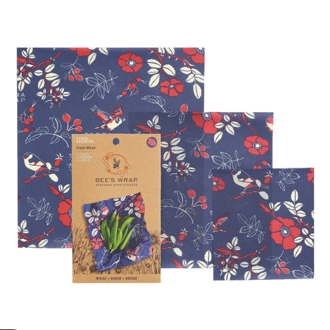 Bees Wrap Assorted 3 Pack offers reusable, plastic-free food wraps with blue backgrounds and red, white, and green floral and bird designs in various sizes. Packaging is centered.