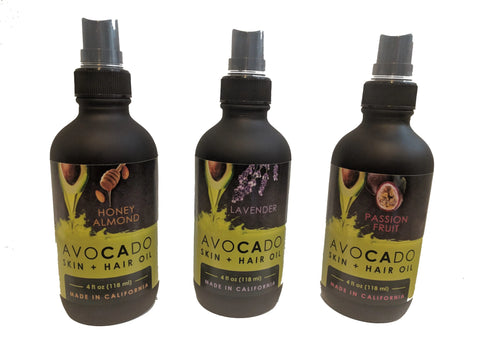 Three 4oz bottles of Bella Vado Avocado Oil Skin & Hair Oil come in Honey Almond, Lavender, and Passion Fruit scents, each with a black cap and scent-image label—ideal as a moisturizer or hair treatment.