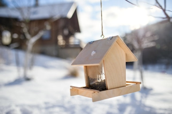 Wooden bird feeder hanging in a snowy outdoor setting