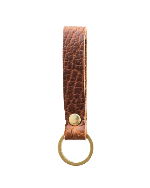 The Bison Standard Key Fob No. 1603 by Homestead Brand features a loop of textured brown leather with a brass rivet and round brass key ring—an American-made accessory that brings timeless style to your everyday essentials.