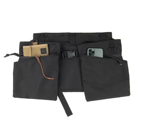 The MIS Game Apron Bag - Black is a water-resistant Packcloth Nylon utility waist pouch with multiple pockets, a buckle closure, adjustable straps, detachable belt, and fits items like a beige zip pouch and phone.