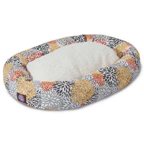 The Majestic Pet Blooms Sherpa Bagel Dog Bed features an oval shape, water-resistant design, soft white plush center, and raised edges with a vibrant yellow, orange, gray, and white floral pattern—ideal for outdoor lounging.