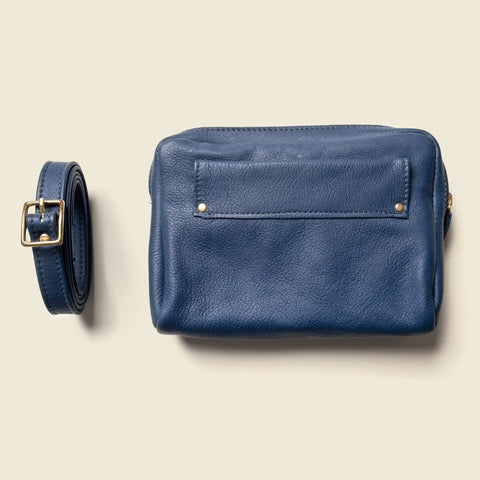 The CASUPO Fanny Pack - Blue is a sustainable leather crossbody bag with a front pocket and gold rivets, shown with a matching detachable strap featuring a gold buckle, displayed on a beige background.