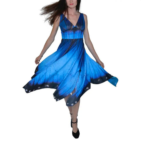 A woman twirls in the Spiritex Blue Morpho Butterfly Dress, featuring a handkerchief hem and flaring blue skirt, set against a plain white background.