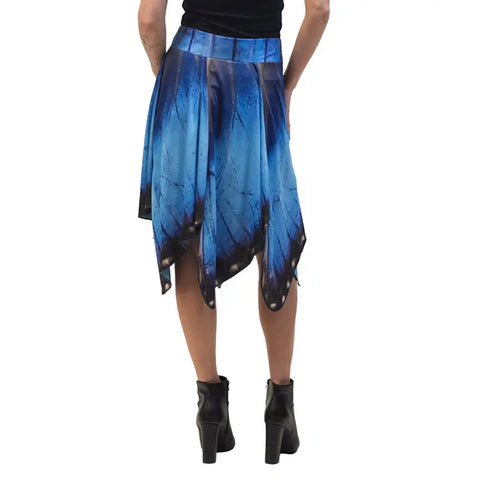 A person is shown from the back wearing a black top, black ankle boots, and the Spiritex Blue Morpho Butterfly Skirt featuring a blue handkerchief-hem with butterfly wing design.