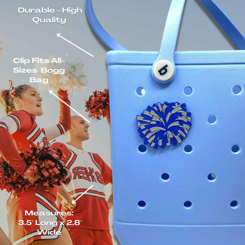 A light blue Bogg Bag features the Chatelet Manufacturing BOGLETS Cheerleading Charm (Blue Pom Pom), compatible with Bogg Bags and other totes. Durable and decorative, its shown clipped to the bag as cheerleaders in red uniforms stand in the background.