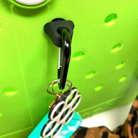 The BOGLETS by Chatelet Manufacturing is a black carabiner keys holder charm accessory attached to a green surface, perfect for organizing keys or valuables in your Bogg Bag.