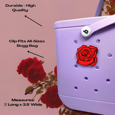A close-up of a lavender Bogg Bag with a Chatelet Manufacturing BOGLETS Flower Charm attached. Text: “Durable - High Quality,” “Clip Fits All-Sizes Bogg Bag,” “Measures: 3 Long x 3.5 Wide.” Red roses bloom in the background.