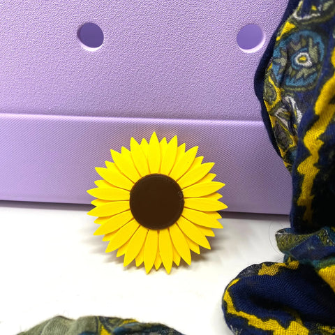 The BOGLETS Flower Charm Accessory by Chatelet Manufacturing, designed for Bogg Bags, adds a cute sunflower touch with its yellow petals and brown center—perfect for customizing your bag or using as a playful charm.