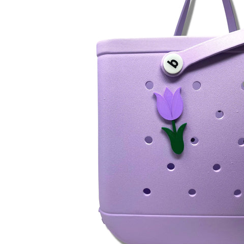 The BOGLETS Flower Charm Accessory by Chatelet Manufacturing is a cute tulip and b button charm for Bogg Bags. It adds a pop of purple to your lavender tote with circular holes, perfect for customizing your bags look.