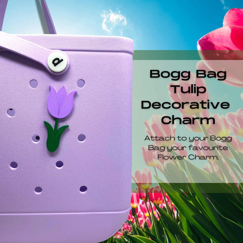 A lavender Bogg Bag with a purple tulip charm from Chatelet Manufacturing’s BOGLETS—Flower Charm Accessory, perfect for customizing your bag, is shown against a tulip field. Add this cute decorative charm or daisy accessory to your Bogg Bag!.