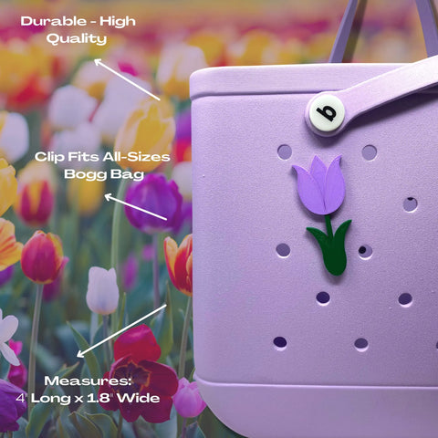 A close-up of Chatelet Manufacturings BOGLETS Flower Charm Accessory on a purple Bogg Bag. White text highlights: Durable - High Quality, Clip Fits All-Size Bogg Bags, Measures 4 L x 1.8 W. Tulips in the background.