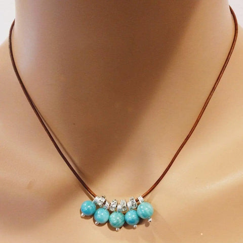 The Silver Green Blue Shell Bead Charm Leather Necklace by Alexa Martha Designs is displayed on a mannequin neck.