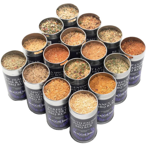 The Gustus Vitae Complete Bougie BBQ Collection - Sweet 16 features open metal tins stacked in a pyramid, each filled with colorful artisanal spice blends and labeled with BBQ rub names like Spicy Curry, Argentinian Chicken, and Pacific Lamb.