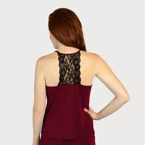 A woman with long red hair is seen from behind wearing the Goodnighties Lace Back Halter Top in burgundy, which features a black lace panel on the upper back. The background is plain and light gray.