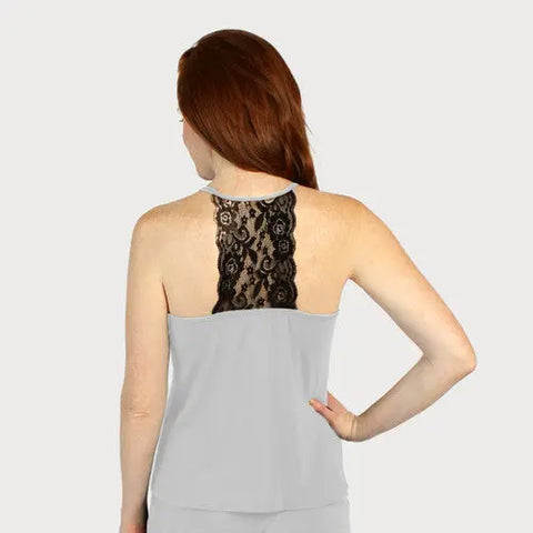 A woman with long red hair is seen from behind, modeling the Goodnighties Lace Back Halter Top in light gray with a black lace center panel. Her left hand on her hip highlights this chic, American-made sleepwear style.