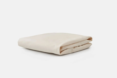The Soft Cotton Baby Bedding Crib Sheet by American Blossom Linens, featuring cozy, breathable fabric in off-white, is neatly folded and displayed on a plain white background.