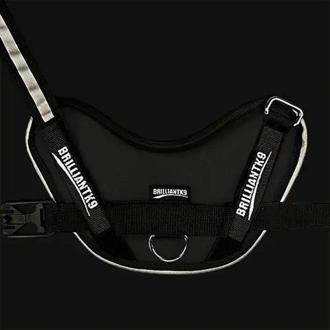The BrilliantK9 Ergonomic Dog Harness for XLarge dogs (80 lbs and up) features reflective trim, multiple BrilliantK9 logos, an adjustable chest strap, plastic buckle, and metal D-ring—shown on a plain black background.