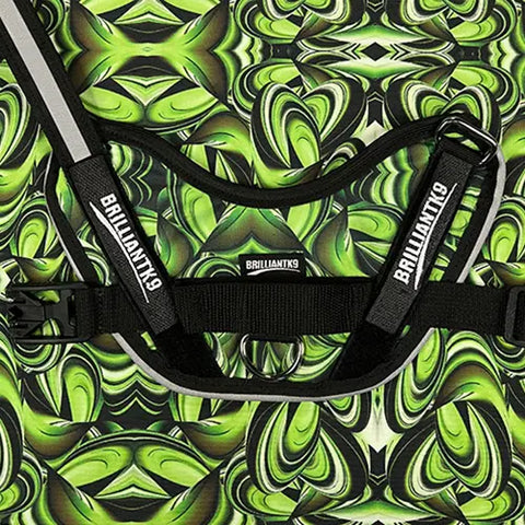 A close-up of the BrilliantK9 Ergonomic Dog Harness for large dogs (50–80 lbs) in a green, black, and white abstract pattern. Branded straps and an adjustable chest strap highlight its soft, durable design against kaleidoscopic green backgrounds.