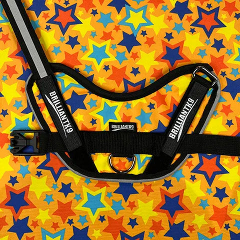 A BrilliantK9 Ergonomic Dog Harness for medium dogs (20 to 45 lbs) is shown on a vibrant background with overlapping blue, orange, and yellow stars.