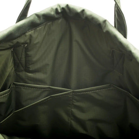 The image shows the inside of the MIS UK Helmet Bag - Camo Green, made from durable, water-resistant Cordura Nylon with two open inner pockets, visible stitching on the lining, and top handles for easy carrying.