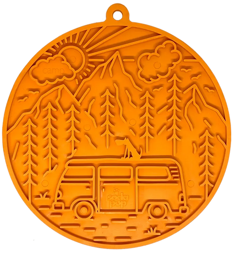 The SodaPup Camp Design EMat Enrichment Lick Mat With Suction Cups is an orange circular mat featuring an embossed dog atop a camper van with trees, mountains, clouds, and sun in the background.