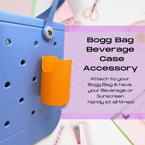 A blue Bogg Bag is shown with an orange FRESHe BAGLETS Can Drink & Water Bottle Holder Charm Accessory by Chatelet Manufacturing attached. Keep your bottles or cans handy on your tote—fits inside or outside the bag. Pink office supplies in background.