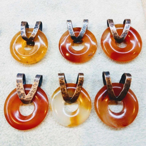 The Alexa Martha Designs Carnelian Gemstone Donut Copper Chain Necklace features a round, amber-brown stone pendant with unique color variations and a hammered copper loop—perfect for fans of rustic style jewelry.