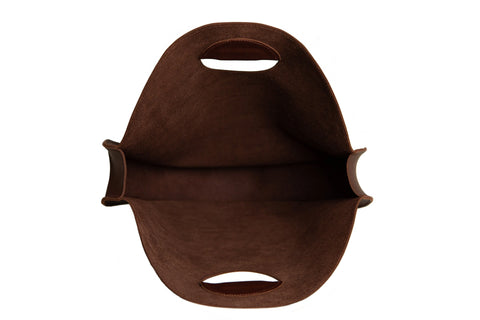 Top view of the Urban Southern Carrollton Circle Tote, an empty brown oval bag with two cut-out handles, made from soft, flexible leather and shown isolated on a white background.