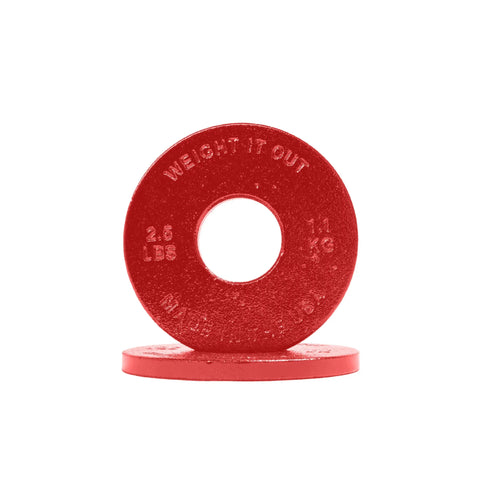 Two red Cast Iron Machined Weight Plate Pairs by Weight It Out: one upright and one flat, each with a large center hole for Olympic bars. The upright plate shows WEIGHT IT OUT, 2.5 LBS, and 1.1 KG—designed for minimal weight variance.